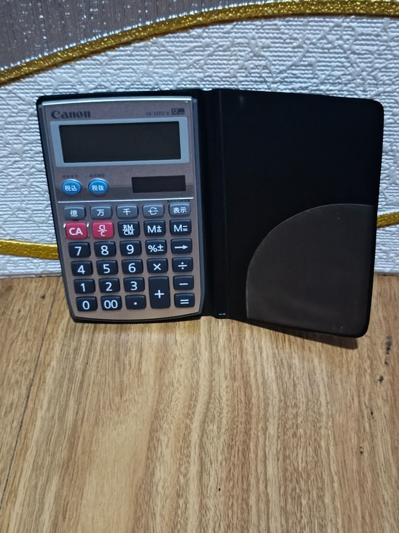 CANON LS-12TU II CALCULATOR (Category: Stationery & School Supplies) located in Makati City. Submitted by nyxhemera26 (Listing ID 1400337140, Image 1). Description: CANON LS-12TU II CALCULATOR - 300 • WORKING. LIKE NEW The product in the image is a Canon LS-12TU II calculator. It is a 12-digit handheld calculator with a soft wallet cover. Tax Function: It has tax calculation functions, including "tax included" (税込) and "tax excluded" (税抜) buttons