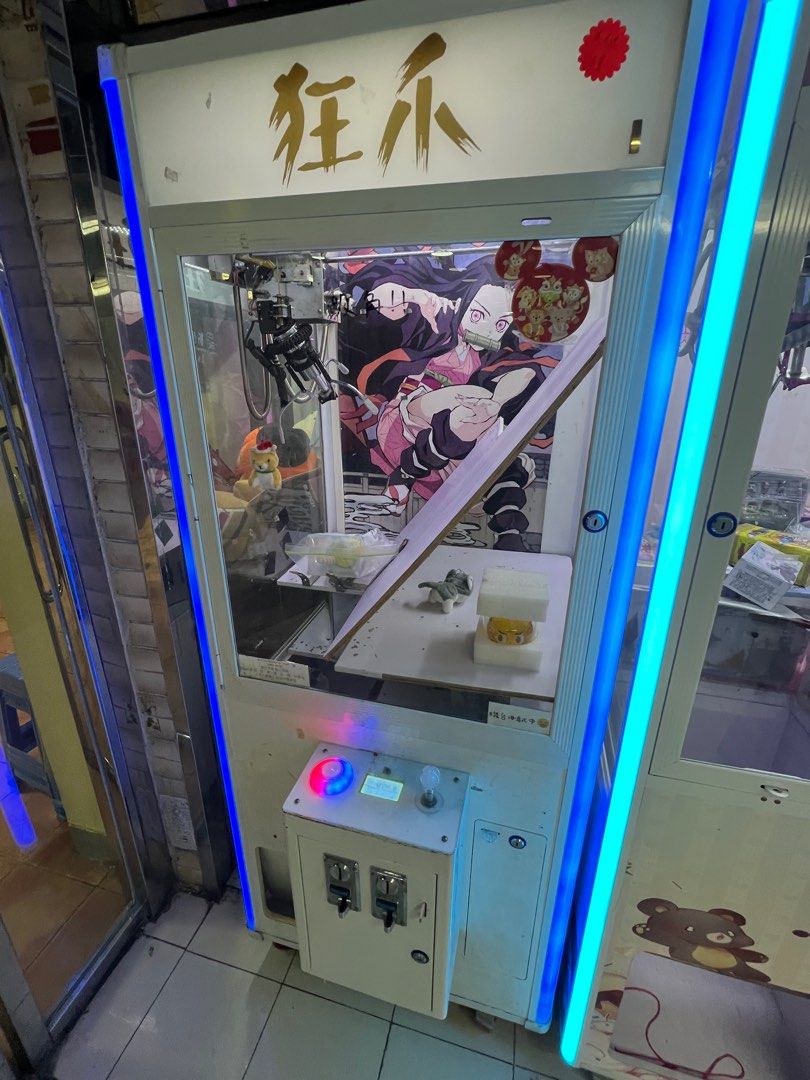 夾公仔機 （分類：互動玩具）位於 Hong Kong。 由 laukwanlong 提交（商品編號 1400505702，圖片 3）。簡介： 這是一台夾娃娃機，機台內有各種娃娃和商品，包括卡通人物玩偶、盒子裝的商品等。機台外觀有紅藍色的燈光裝飾，機台上有投幣孔和操作按鈕。機台內有爪子，可以用來抓取裡面的商品。。