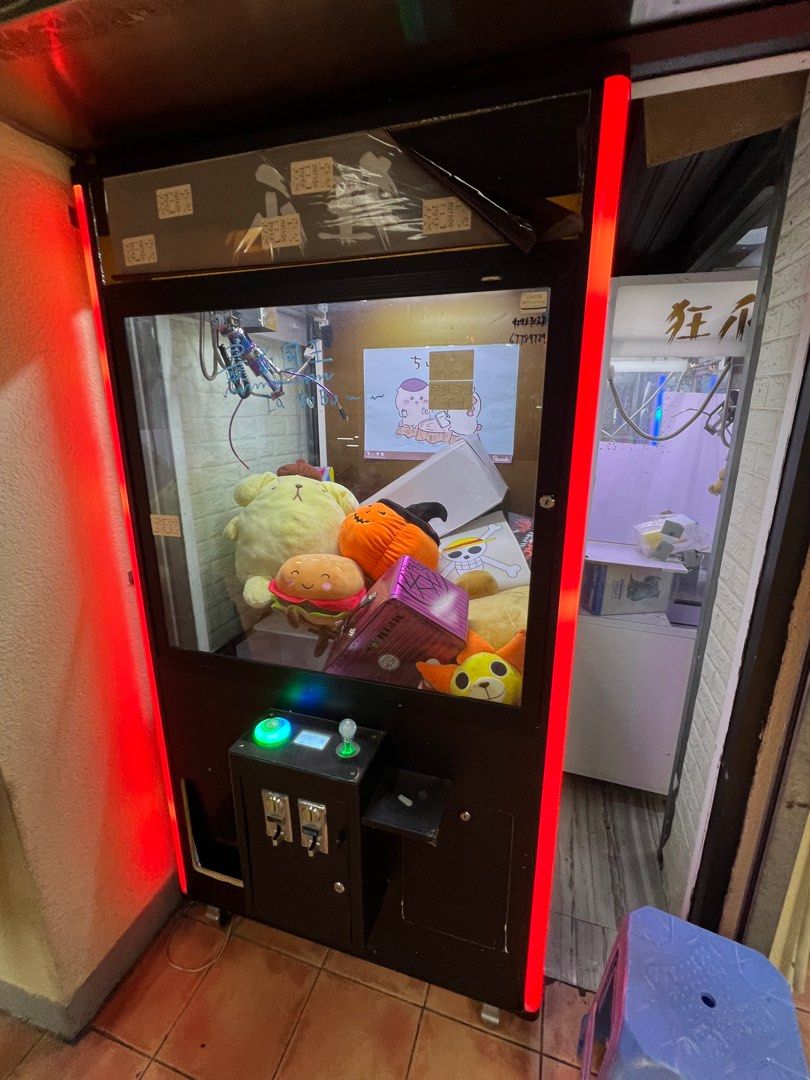 夾公仔機 （分類：互動玩具）位於 Hong Kong。 由 laukwanlong 提交（商品編號 1400505702，圖片 4）。簡介： 這是一台夾娃娃機，機台內有各種娃娃和商品，包括卡通人物玩偶、盒子裝的商品等。機台外觀有紅藍色的燈光裝飾，機台上有投幣孔和操作按鈕。機台內有爪子，可以用來抓取裡面的商品。。