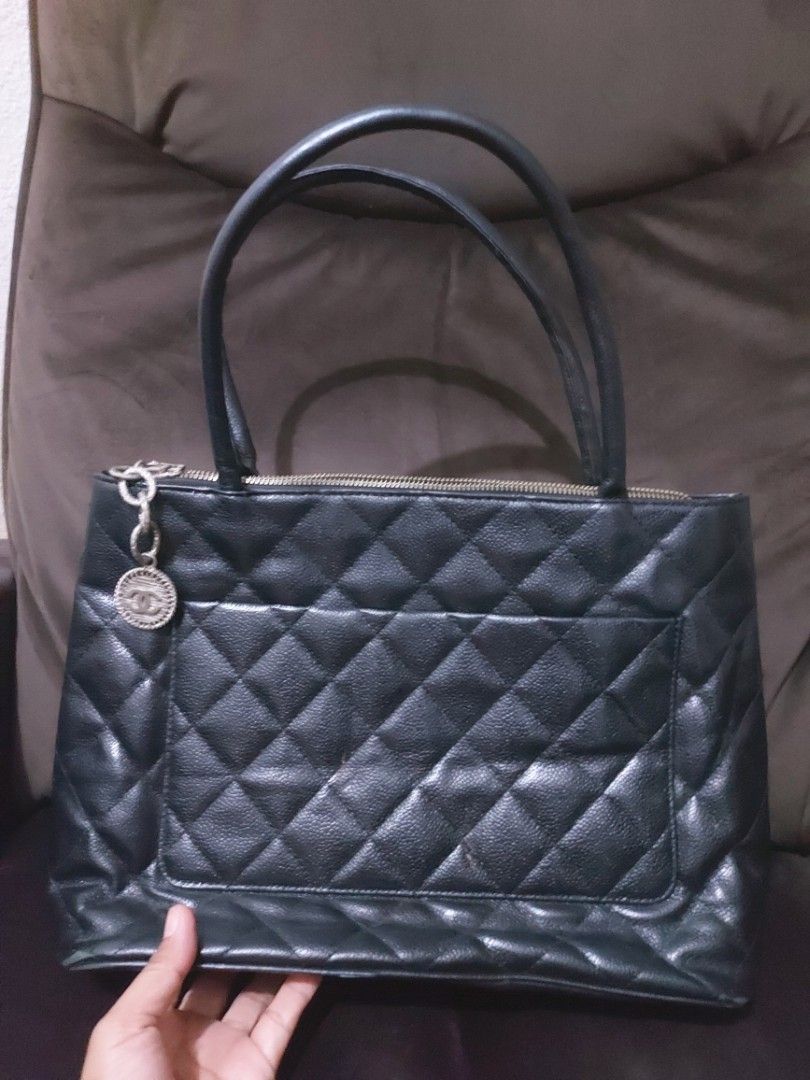 Chanel Black Quilted Tote Bag (Category: Luxury Bags & Wallets) located in Tagum. Submitted by padaslydia82022 (Listing ID 1400496819, Image 2). Description: - Black quilted tote bag - Double handles - Large CC logo - Zipper closure - Silver-tone charm - Multiple interior compartments - Chanel label - Leather material - Shows wear on the bottom.