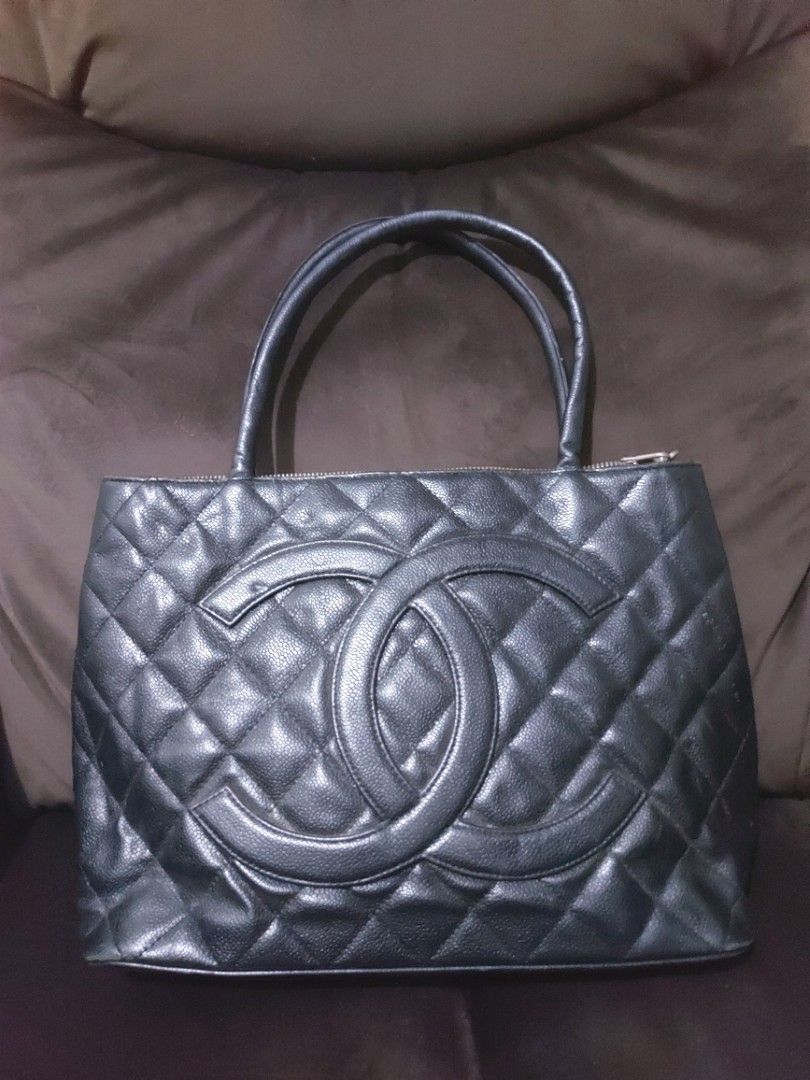 Chanel Black Quilted Tote Bag (Category: Luxury Bags & Wallets) located in Tagum. Submitted by padaslydia82022 (Listing ID 1400496819, Image 1). Description: - Black quilted tote bag - Double handles - Large CC logo - Zipper closure - Silver-tone charm - Multiple interior compartments - Chanel label - Leather material - Shows wear on the bottom.