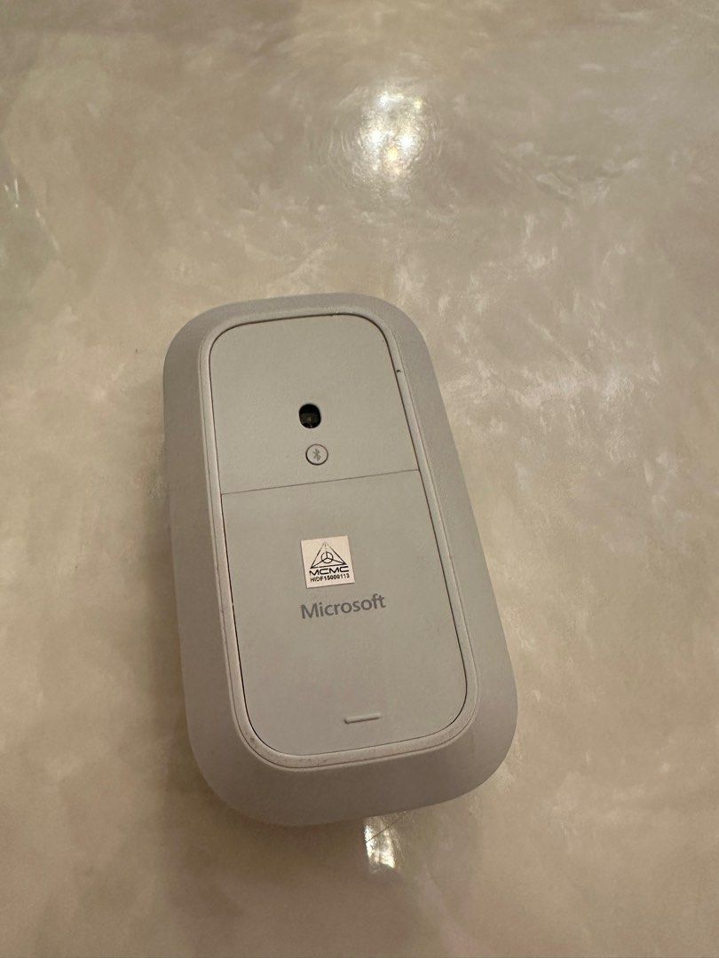 Microsoft Surface Mouse (Category: Mouse & Mousepads) located in Shah Alam. Submitted by afiqahmad7 (Listing ID 1400534570, Image 2). Description: - Microsoft Surface Mouse - Color: Light Grey - Simple, ergonomic design - Features a scroll wheel - Microsoft logo and product label visible on the underside.