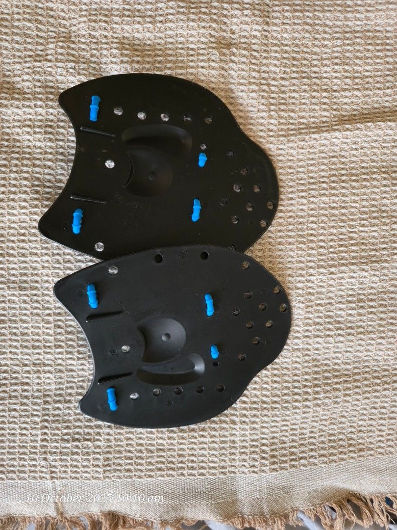 Swimfit Hand Paddles (Category: Water Sports) located in Mandaluyong City. Submitted by zeus2021 (Listing ID 1400430069, Image 3). Description: Swimfit hand paddles for swim training. Features a black paddle with blue straps and accents. Includes a mesh carrying bag. The paddles have multiple holes for water flow and are designed to improve swimming technique and strength. The paddles are designed to fit the hand. used once in Boracay..