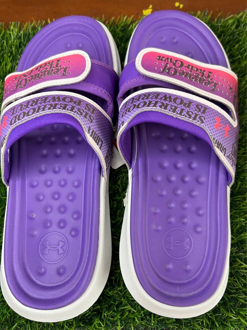 Under Armour UA W Ansa Studio IWD SL Slides (Category: Slippers and slides) located in Manila. Submitted by phatpen (Listing ID 1400450340, Image 2). Description: These Under Armour slides feature a purple and white design with the words "Sisterhood is Powerful" and "League of Their Own". size 8 US,. The slides are new with the original tag still attached, showing a price of $49.99..