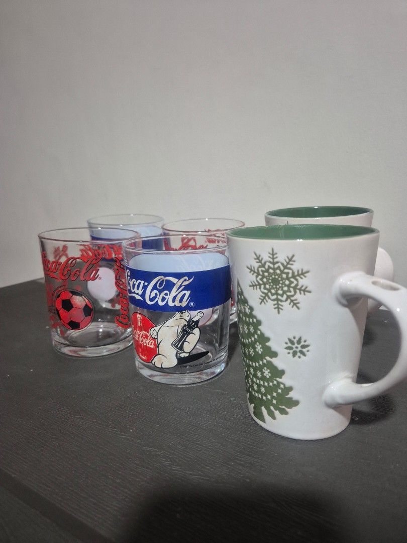 Christmas Mugs and Coca-Cola Glasses Set (Category: Coffee & Tea Tableware) located in Pasig City. Submitted by rubyspick (Listing ID 1400650320, Image 1). Description: Set includes two Christmas-themed mugs with snowflake and tree designs, and three Coca-Cola glasses. The mugs have a white exterior and green interior. The Coca-Cola glasses feature various designs, including a polar bear and a soccer ball. Perfect for adding a festive touch to yo
