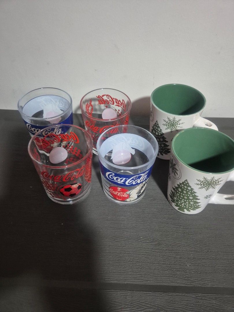 Christmas Mugs and Coca-Cola Glasses Set (Category: Coffee & Tea Tableware) located in Pasig City. Submitted by rubyspick (Listing ID 1400650320, Image 2). Description: Set includes two Christmas-themed mugs with snowflake and tree designs, and three Coca-Cola glasses. The mugs have a white exterior and green interior. The Coca-Cola glasses feature various designs, including a polar bear and a soccer ball. Perfect for adding a festive touch to yo