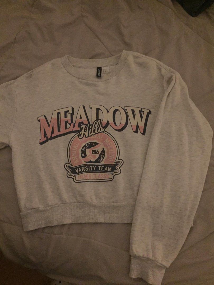 H&M Divided Meadow Hills Sweatshirt (Category: Longsleeves) located in Manila. Submitted by ren._. (Listing ID 1400724040, Image 1). Description: - H&M Divided sweatshirt - Size: XS - Color: Light gray - Graphic: "Meadow Hills Varsity Team" (pink and black) - Features: Crew neck, long sleeves - Material: Soft, fleece-like interior.