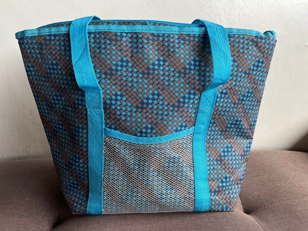 Insulated Cooler Bag (Category: Food Organization & Storage) located in Quezon City. Submitted by cristintin (Listing ID 1400622627, Image 1). Description: Insulated cooler bag is perfect for keeping your food and drinks cold. It features a blue and brown geometric pattern, a mesh pocket on the front, and sturdy blue handles. The interior is lined with a silver insulated material. It has a zipper closure to keep contents secure. Made in China..