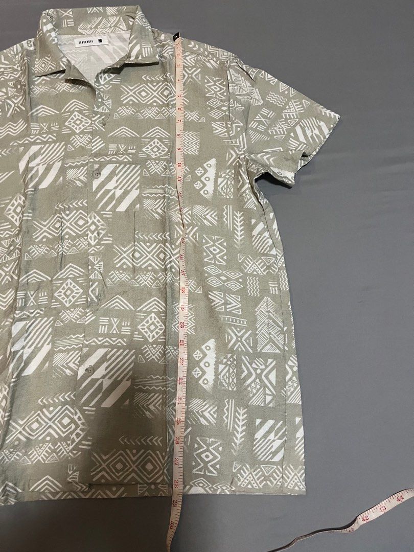 Terranova Printed Short Sleeve Shirt (Category: Tshirts & Polo Shirts ) located in Tarlac. Submitted by johnjohnjohn23 (Listing ID 1400647676, Image 2). Description: - Terranova short sleeve shirt - Unique printed design - Collared neckline - Button-down closure - Neutral color with white geometric patterns - Size: Medium - Measurements in images - Perfect for casual wear.