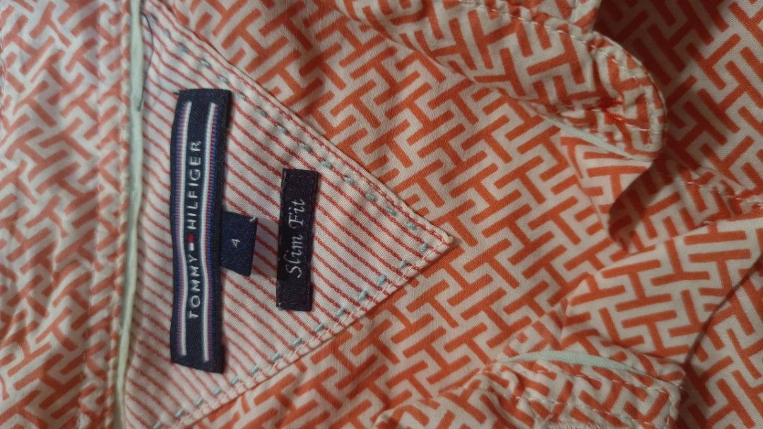 Tommy Hilfiger Slim Fit polo blouse (Category: Blouses) located in Muntinlupa City. Submitted by amara211629 (Listing ID 1400639976, Image 2). Description: - Tommy Hilfiger short-sleeved shirt - Vibrant orange color - Size 4, slim fit - Button-down front cotton - Collared neckline - Stylish geometric pattern - Features the Tommy Hilfiger logo * M- Semi Large RFS: I'm M but shoulder width is too long for me. .