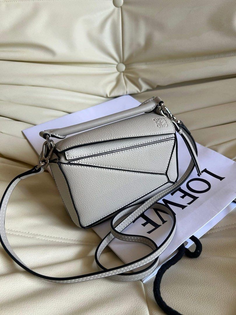 Loewe Puzzle Mini Bag (with box) (Category: Luxury Bags & Wallets) located in Taytay. Submitted by darkswan016 (Listing ID 1400826193, Image 1). Description: Bought this from carousell 2 months ago. Rfs: too small for me. Cannot guarantee authenticity. - Loewe Puzzle Mini Bag - Light grey color - Unique geometric design - Top handle and detachable shoulder strap - Interior with herringbone lining - Made in Spain.