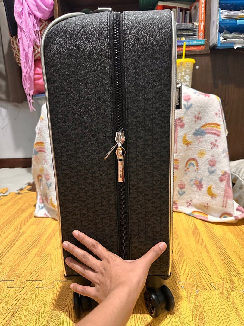 Michael Kors Carry-on Luggage Preloved (Category: Luxury Bags & Wallets) located in Cebu City. Submitted by balikbayanboxitems (Listing ID 1400889024, Image 2). Description: - Michael Kors carry-on luggage - Signature pattern - Silver trim - Travel-themed stickers - Gray interior lining - Multiple compartments - Securing strap - Zippered closure - Retractable handle - Wheels for easy transport.