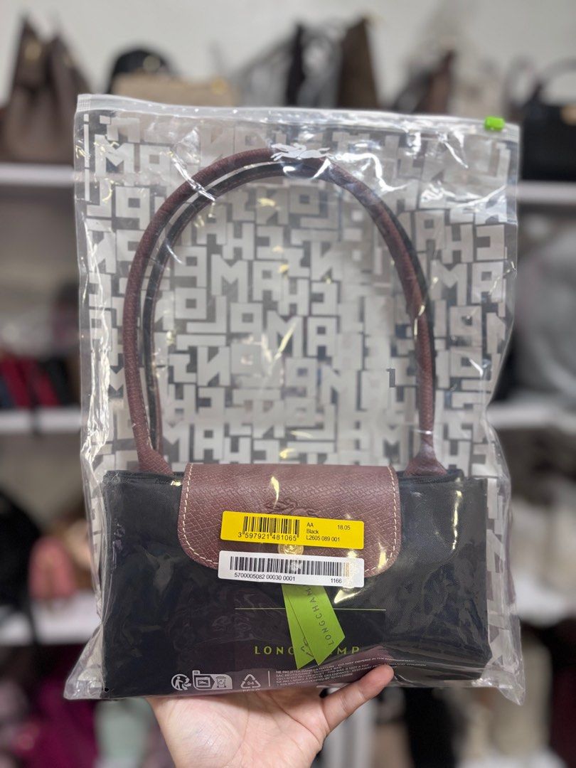 Longchamp Long handle medium black (Category: Luxury Bags & Wallets) located in Quezon City. Submitted by aloracollections_ (Listing ID 1401154108, Image 1). Description: - Authentic Longchamp Le Pliage handbag - Color: Black with brown leather accents - Features flap closure with gold-tone button and Longchamp logo - Includes original tags - New and unused condition - Still in original packaging.
