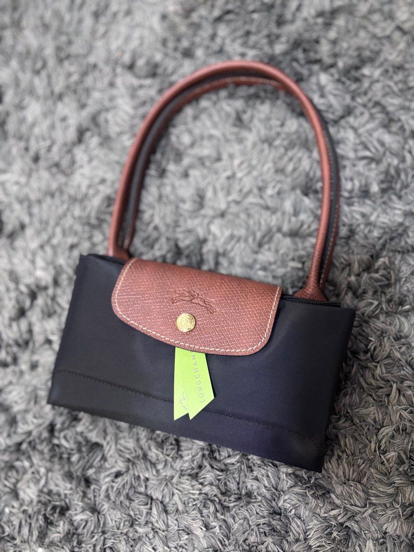 Longchamp Long handle medium black (Category: Luxury Bags & Wallets) located in Quezon City. Submitted by aloracollections_ (Listing ID 1401154108, Image 3). Description: - Authentic Longchamp Le Pliage handbag - Color: Black with brown leather accents - Features flap closure with gold-tone button and Longchamp logo - Includes original tags - New and unused condition - Still in original packaging.