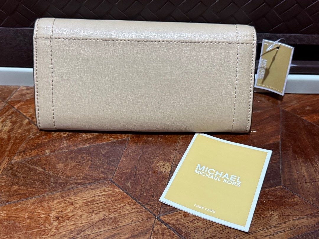 Michael Kors Beige Wallet (Category: Luxury Bags & Wallets) located in San Pedro. Submitted by cathy_paras (Listing ID 1401141736, Image 2). Description: Brand New Michael Kors Kinsley large carryall leather wallet. *The wallet is a bifold or trifold design with a gold-tone clasp featuring the “MICHAEL KORS” logo. *It is made of leather and has a structured, envelope-style flap. *The color appears to be a neutral shade, such as beige or nude. *Th