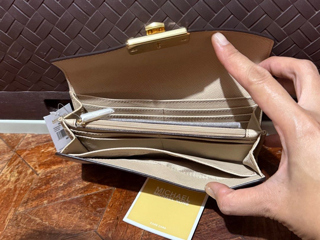 Michael Kors Beige Wallet (Category: Luxury Bags & Wallets) located in San Pedro. Submitted by cathy_paras (Listing ID 1401141736, Image 3). Description: Brand New Michael Kors Kinsley large carryall leather wallet. *The wallet is a bifold or trifold design with a gold-tone clasp featuring the “MICHAEL KORS” logo. *It is made of leather and has a structured, envelope-style flap. *The color appears to be a neutral shade, such as beige or nude. *Th