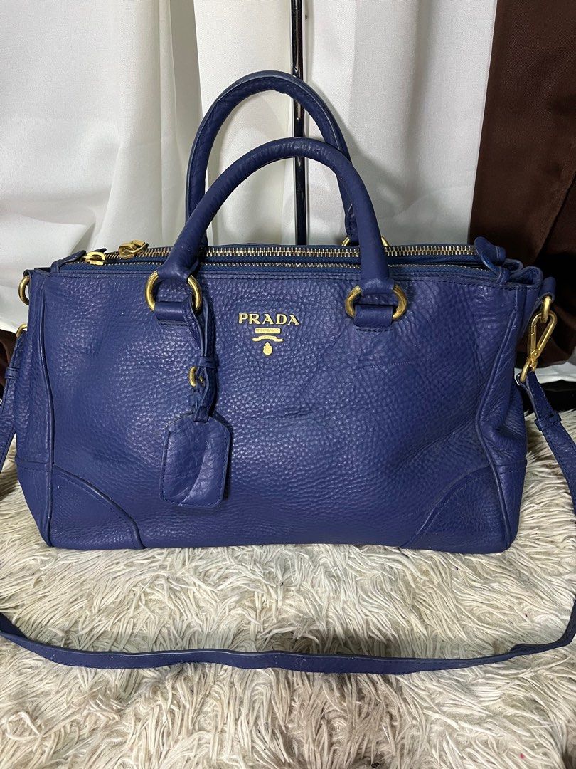 Prada Blue Leather Handbag (Category: Luxury Bags & Wallets) located in Caloocan City. Submitted by witchywardrobe (Listing ID 1401142585, Image 1). Description: (Authenticity not claim) Big Capacity Authentic Prada handbag in a beautiful blue color. Features gold-tone hardware, including zippers and clasps. Includes a detachable shoulder strap and a leather tag. The interior has multiple compartments and a Prada logo. The bag has double handles 