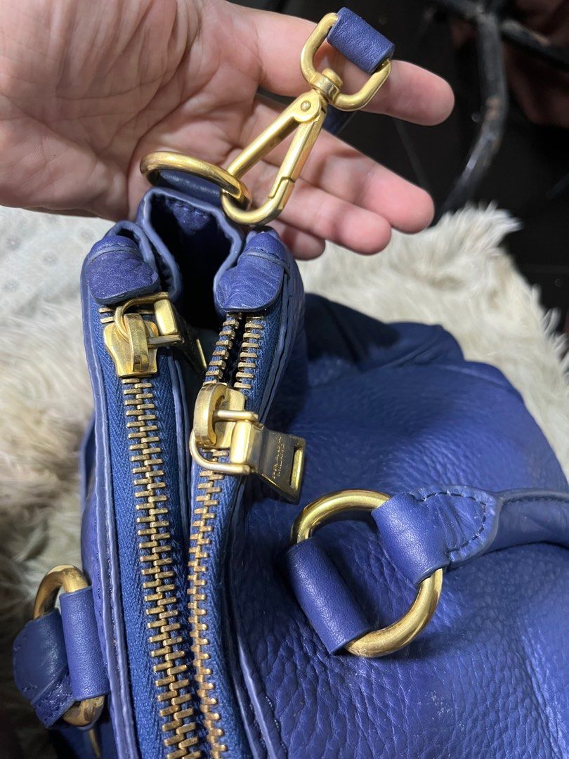 Prada Blue Leather Handbag (Category: Luxury Bags & Wallets) located in Caloocan City. Submitted by witchywardrobe (Listing ID 1401142585, Image 2). Description: (Authenticity not claim) Big Capacity Authentic Prada handbag in a beautiful blue color. Features gold-tone hardware, including zippers and clasps. Includes a detachable shoulder strap and a leather tag. The interior has multiple compartments and a Prada logo. The bag has double handles 
