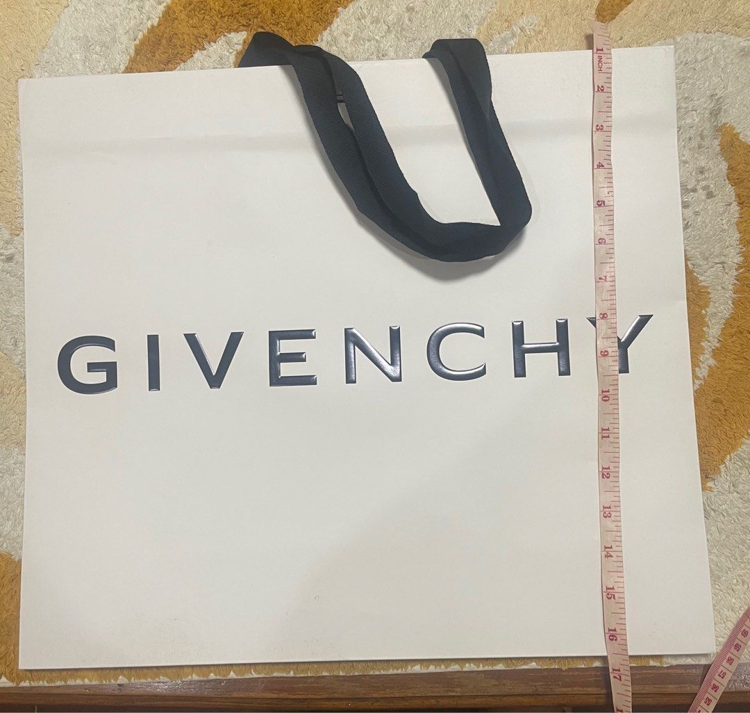 Authentic Givenchy Paper Bag (Category: Luxury Bags & Wallets) located in Manila. Submitted by onlineshopbyyou (Listing ID 1396213435, Image 2). Description: - Authentic Givenchy paper bag - White exterior - Black Givenchy logo - Black handles - Dimensions: Approximately 19 inches wide x 17 inches tall - Perfect for gifts or collectors.