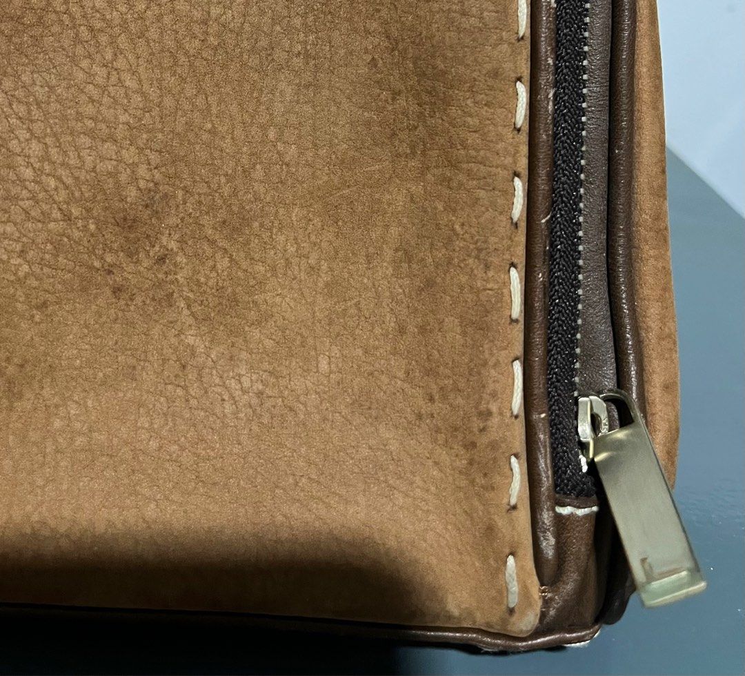 Lancel Paris Brown Handbag (Category: Luxury Bags & Wallets) located in San Fernando. Submitted by gemsfndr (Listing ID 1396257332, Image 2). Description: - Lancel Paris handbag - Dual-tone brown design - Lighter brown suede-like material on front pockets - Top handle - Zip closure - Dark brown fabric interior lining with Lancel Paris logo - Multiple compartments - Metal clasp closure.
