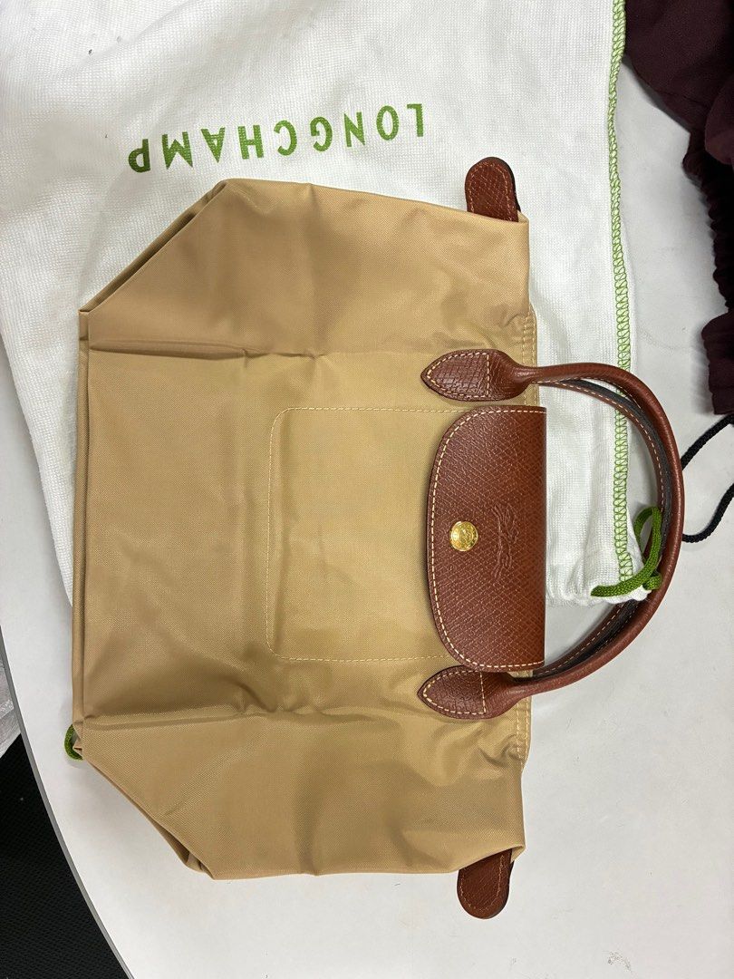 Longchamp Le Pliage Handbag (Category: Luxury Bags & Wallets) located in Manila. Submitted by thrifters.mnl.28 (Listing ID 1396111754, Image 1). Description: - Authentic Longchamp Le Pliage - Tan nylon exterior - Brown leather handles and accents - White interior - Includes Longchamp dust bag - Features Longchamp logo on zipper pull - Made in China.