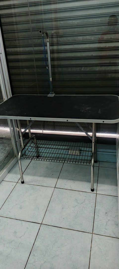Pet Grooming Table with Adjustable Arm (Category: Homes & Other Pet Accessories) located in Quezon City. Submitted by marizalyanna (Listing ID 1396165412, Image 2). Description: - Black, textured tabletop - Sturdy metal frame - Adjustable grooming arm with blue restraint loop - Wire mesh shelf for storage - Perfect for various pet grooming tasks Loc: cubao 110x60.