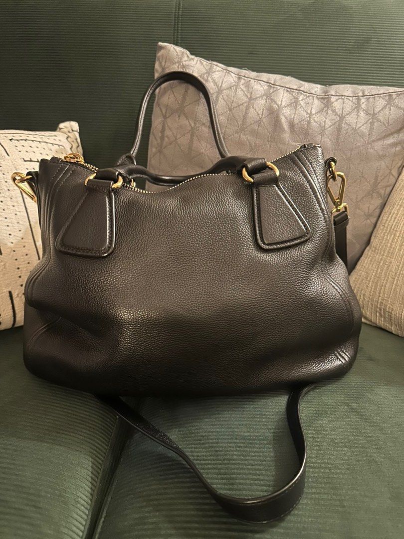 Prada Leather Handbag (Category: Luxury Bags & Wallets) located in Manila. Submitted by kaitdeclutters (Listing ID 1396209878, Image 2). Description: - Authentic Prada handbag - Black textured leather - Gold-tone hardware - Top handle and detachable shoulder strap - Includes authenticity cards - Protective feet All authenticity cards still included Original dust bag included .