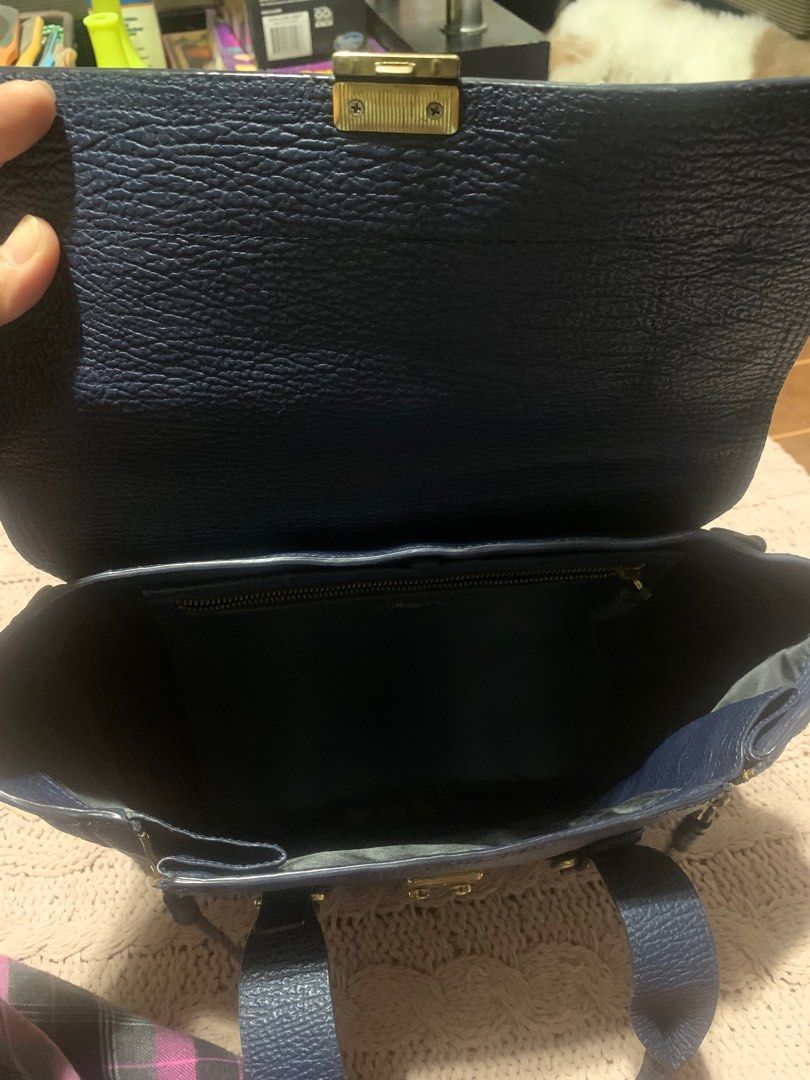 3.1 Phillip Lim Navy Leather Satchel (Category: Luxury Bags & Wallets) located in Bulacan. Submitted by love2loved (Listing ID 1401308643, Image 3). Description: Navy blue leather satchel bag from 3.1 Phillip Lim. Features a top handle, a flap closure with a gold-tone clasp, and gold-tone hardware. Includes two exterior zip pockets and a spacious interior. The interior has a zip pocket with the brand's logo. The zipper has a YKK logo. The bag has