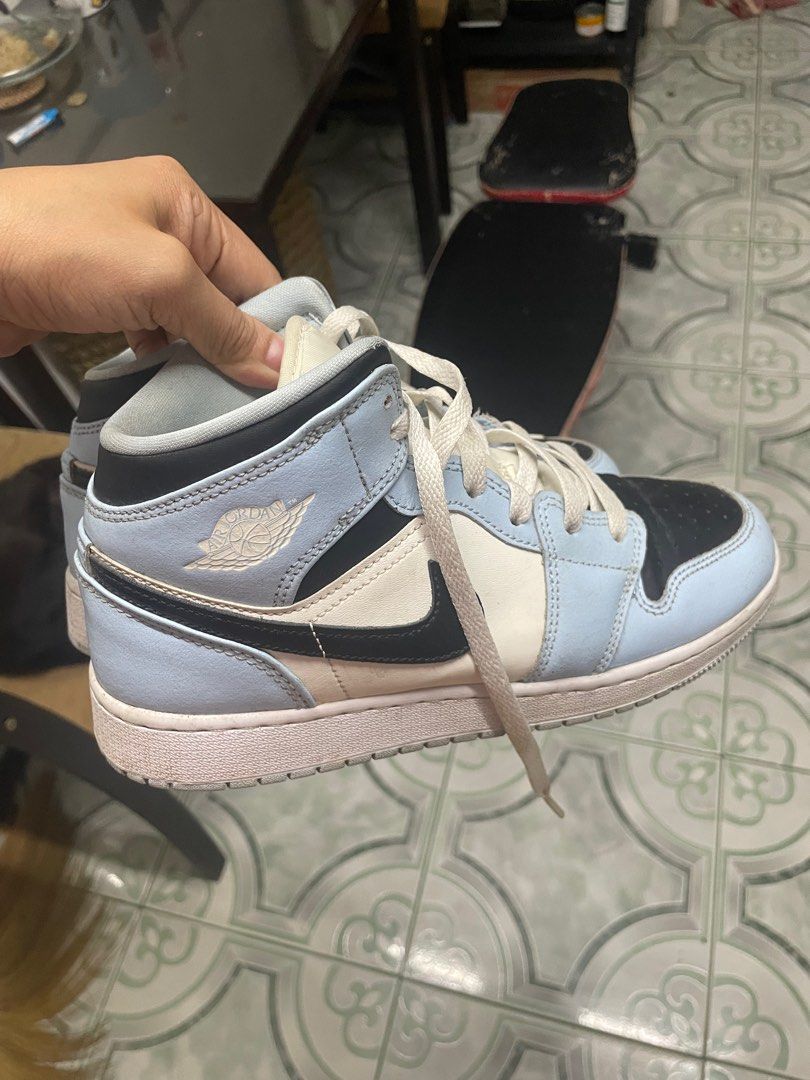 Air Jordan 1 Mid Light Blue Black (Category: Sneakers) located in Pasig City. Submitted by kyla792980 (Listing ID 1401219575, Image 2). Description: Air Jordan 1 Mid in a light blue, black, and white colorway. Features the iconic Air Jordan wings logo on the side. The size is US 6.5Y. The shoes have white laces and a light blue and black design. The sole is white. kasya po sa 7.5 wms size.. declutter:) nabili ko sya sa footlcker sg.