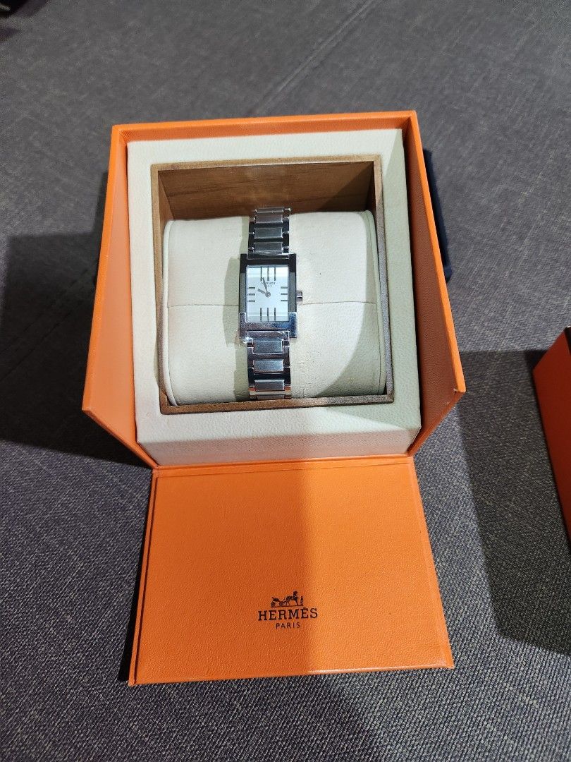 Hermes Watch with Box (Category: Luxury Watches) located in Quezon City. Submitted by joicee_08 (Listing ID 1401281949, Image 2). Description: - Original Hermes watch - Rectangular face - Silver-tone metal band (stainless) - Includes original orange Hermes box.