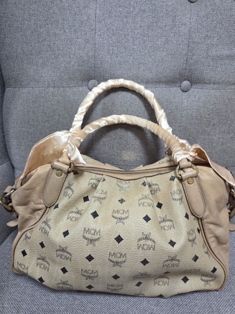 MCM Handbag (Category: Luxury Bags & Wallets) located in Muntinlupa City. Submitted by cpar07 (Listing ID 1401263300, Image 2). Description: - Authentic MCM handbag - Signature logo pattern - Beige exterior - Shoulder bag style - Matching handle with satin-like finish - Interior zipper pocket - Includes brand tag.