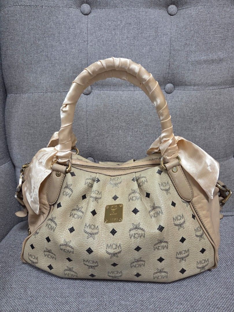MCM Handbag (Category: Luxury Bags & Wallets) located in Muntinlupa City. Submitted by cpar07 (Listing ID 1401263300, Image 1). Description: - Authentic MCM handbag - Signature logo pattern - Beige exterior - Shoulder bag style - Matching handle with satin-like finish - Interior zipper pocket - Includes brand tag.