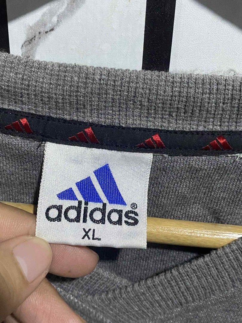 Adidas V-Neck Sweatshirt XL (Category: Coats, Jackets and Outerwear) located in Manila. Submitted by aurafits (Listing ID 1401530025, Image 2). Description: Vintage Adidas sweatshirt in gray with black and red accents. Features the Adidas logo on the front and sleeves. It has a V-neck design and is size XL. The sweatshirt has the classic three stripes on the sleeves. The back of the sweatshirt is plain gray. No issue excellent condition Dimes: 23