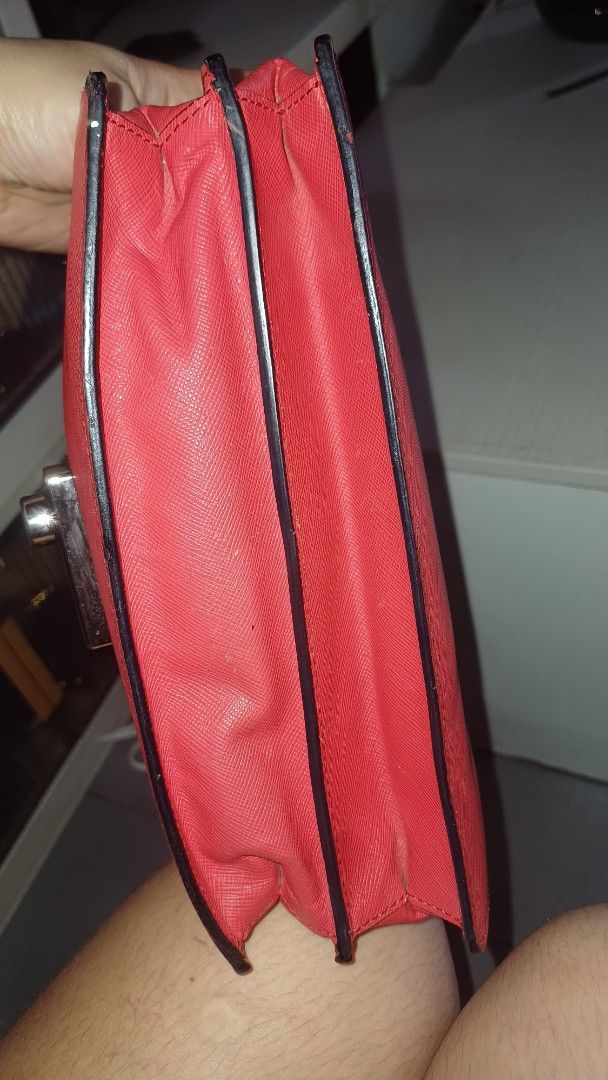 Prada Red Crossbody Bag (Category: Luxury Bags & Wallets) located in Lemery. Submitted by venus23 (Listing ID 1401484272, Image 3). Description: prada crossbody bag features a vibrant red exterior with a unique textured finish. It has a flap closure with a metal clasp. The bag includes a detachable strap and multiple compartments inside. The interior is black with a red lining. The bag has a small stain on the front. The bag has a tag with the nu
