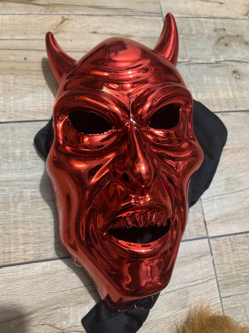 Red Devil Mask with black hood (Category: Face Care) located in Paranaque City. Submitted by zac.sei (Listing ID 1401504100, Image 1). Description: - Red devil mask with horns - Features a detailed face with an open mouth and sharp teeth - Made of shiny, reflective material - Includes black fabric attached to the back as is with cracks .