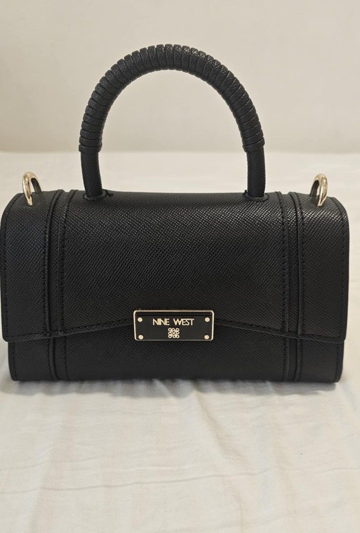 Nine West Black Handbag with Top Handle (Category: Luxury Bags & Wallets) located in Manila. Submitted by bry_d (Listing ID 1396459068, Image 1). Description: - Nine West handbag - Structured design - Top handle and detachable shoulder strap - Rectangular shape with flap closure - Features a small metal logo - Includes dust bag - Gold-toned hardware.