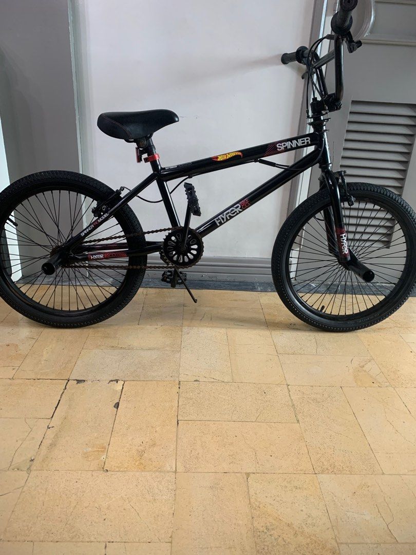 Spinner Hyper 20" BMX Bike (Category: Bicycles) located in Manila. Submitted by mjuanitoch92279 (Listing ID 1396413669, Image 3). Description: - Black Spinner Hyper BMX bike - Black frame, tires, and seat - Features a Hot Wheels logo - Includes chain guard and pegs.