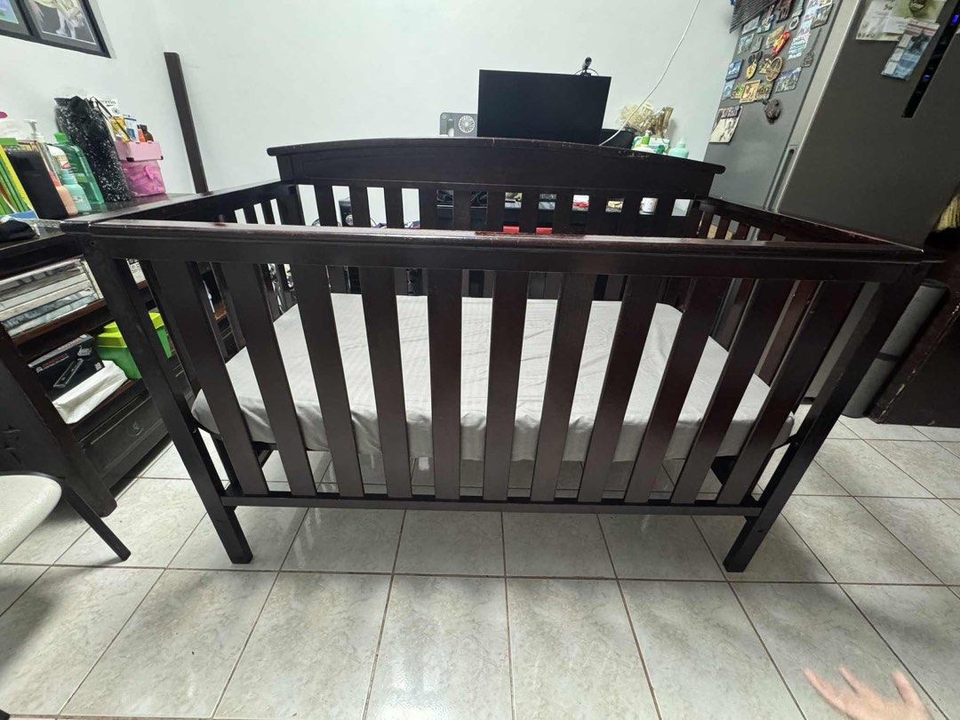 Wooden Baby Crib (Category: Cots & Cribs) located in Manila. Submitted by mimarias (Listing ID 1396345180, Image 3). Description: - Dark brown wooden baby crib - Includes mattress with grey sheet - Slatted sides and curved headboard - Sturdy and well-constructed - Perfect for babies and toddlers.