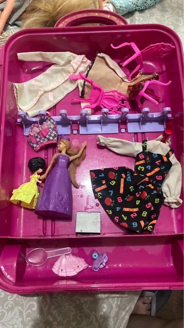 Barbie Doll , Bag and Accessories Set (Category: Kids Toys) located in Quezon City. Submitted by jackpotdecluttering (Listing ID 1396540641, Image 3). Description: - Complete doll set with multiple dolls. - Includes various outfits and accessories. - Comes in a pink carrying case. - Case features a handle and wheels for easy transport. - Accessories include hangers and a bead organizer..