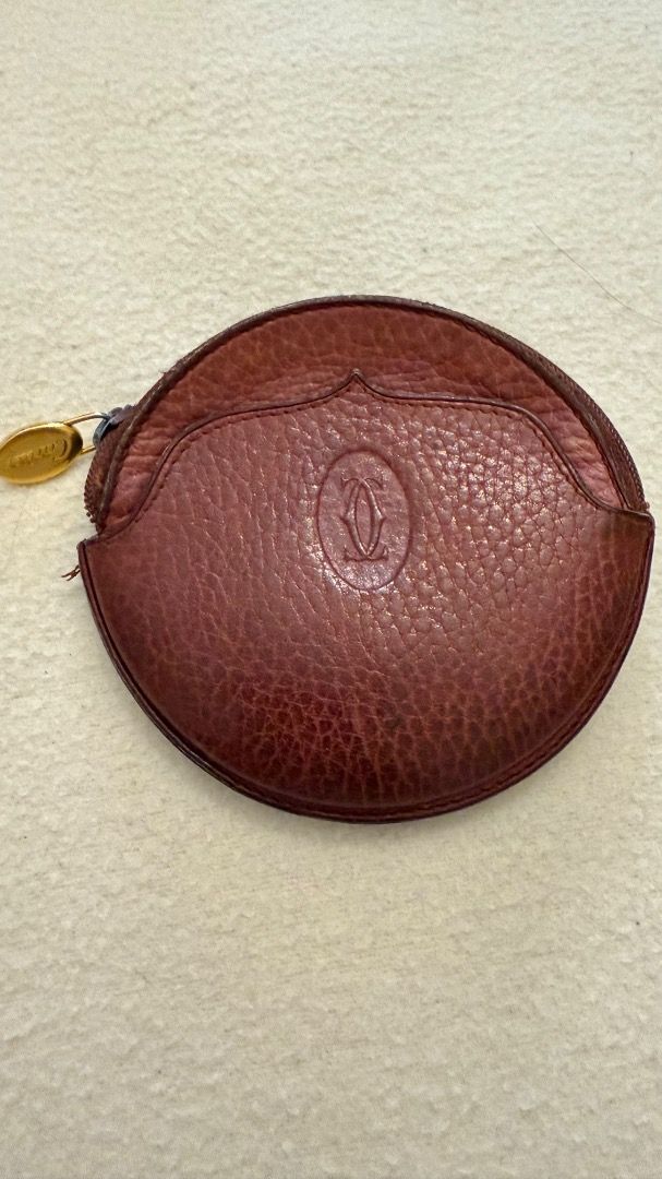 Cartier Round Coin Purse (Category: Luxury Bags & Wallets) located in Cavite. Submitted by rcmontoya (Listing ID 1396623797, Image 1). Description: - Authentic Cartier coin purse - Round shape - Deep reddish-brown textured leather - Gold-tone zipper pull - Embossed Cartier logo - Zipper closure - Small front pocket.