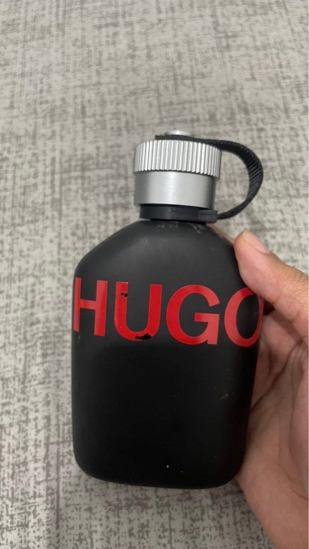 Hugo Boss Just Different Eau de Toilette (Category: Fragrance & Deodorants) located in Manila. Submitted by trishaarciga (Listing ID 1396479435, Image 1). Description: - Hugo Boss Hugo Eau de Toilette - Black bottle with a red "HUGO" logo - Silver cap with a black strap - Minor imperfections present Unsprayed full bottle.