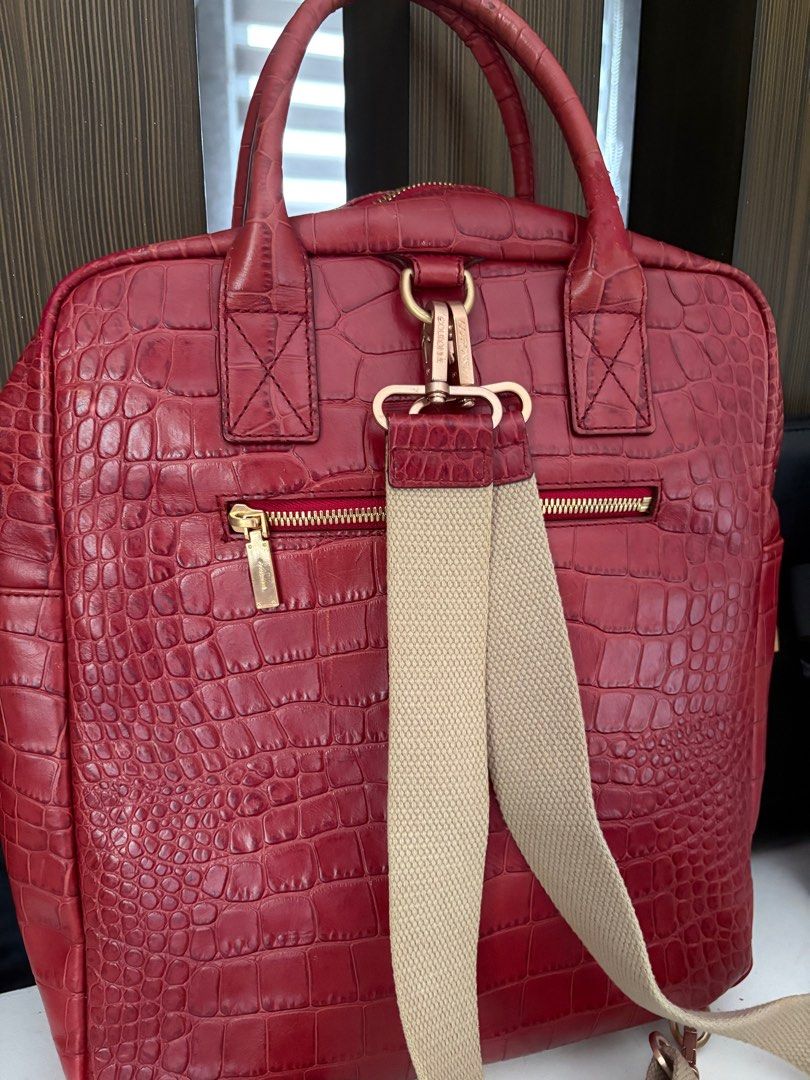 Couronne Red Croc-Embossed Backpack (Category: Luxury Bags & Wallets) located in Cavite. Submitted by misa_destash (Listing ID 1396866641, Image 2). Description: Couronne handbag features a red croc-embossed exterior with gold-tone hardware. It has a top handle and a detachable backpack straps. The interior includes a zippered pocket. The bag has a gold-tone lock with the Couronne logo. The bag has a rectangular shape with a zipper closure. Authe