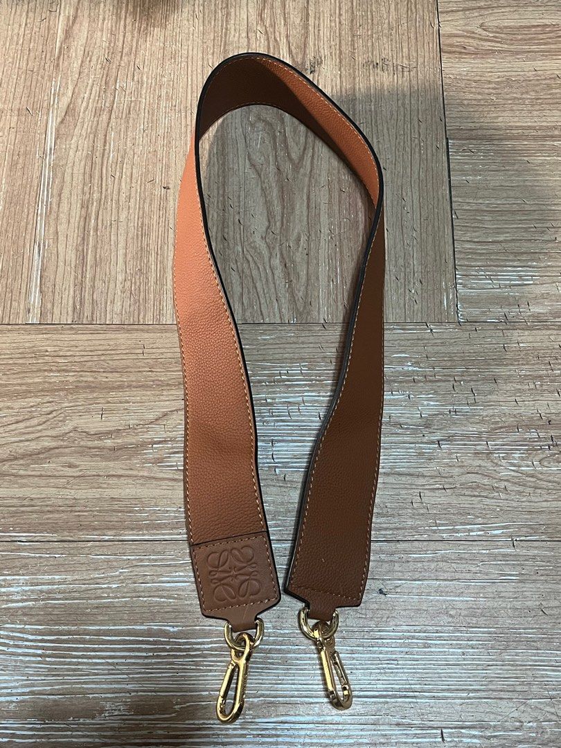 Loewe Leather Bag Strap (Category: Luxury Bags & Wallets) located in Carmen. Submitted by by_your_stuff (Listing ID 1396863686, Image 1). Description: Genuine Loewe bag strap in brown leather. Features gold-tone hardware with the Loewe logo engraved on the clasps and the strap itself. "Made in Spain" is visible on the strap. The strap is two-toned, with a lighter brown on one side and a darker brown on the other..