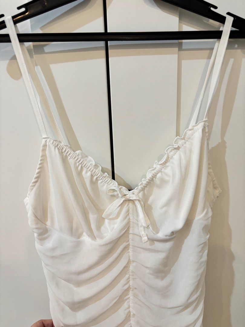 H&M White Ruffled Mini Dress (Category: Dresses) located in Pasay City. Submitted by averycontent (Listing ID 1397136659, Image 1). Description: - H&M white mini dress - Size: M - Features: - Ruffled neckline - spaghetti straps - Ruched bodice - Small bow detail - Bodycon fit - Perfect for casual wear or layering.