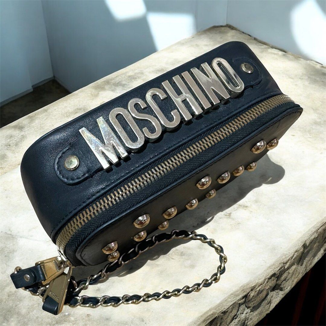 MOSCHINO Limited edition Studded camera/Vanity clutch (Category: Luxury Bags & Wallets) located in Bulacan. Submitted by theclosetsale.ph (Listing ID 1397339608, Image 2). Description: Moschino Limited edition Studded camera/Vanity clutch •Made in Italy •Genuine leather • gold hardwares and leather/chain strap • Excellent condition • Very rare and unique design • Chains are attached on the zipper pullers. Clutch style when closed, super unique •i