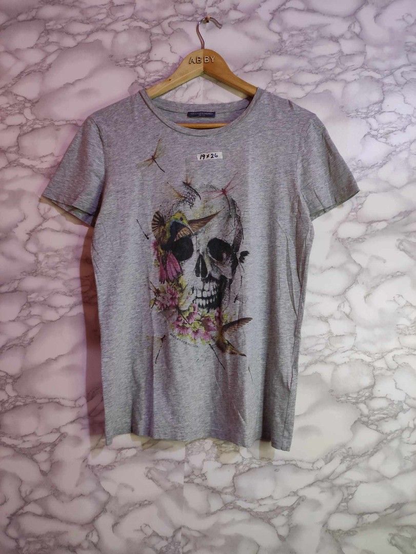 Alexander McQueen Skull Graphic T-shirt (Category: Tshirts & Polo Shirts ) located in Bulacan. Submitted by 2nd_base (Listing ID 1401709205, Image 1). Description: -width 19/length 26 - Features a skull graphic with floral and hummingbird details - Grey crew neck - Made in Italy - Size 40 - Short sleeves - Classic fit - Unique and stylish.