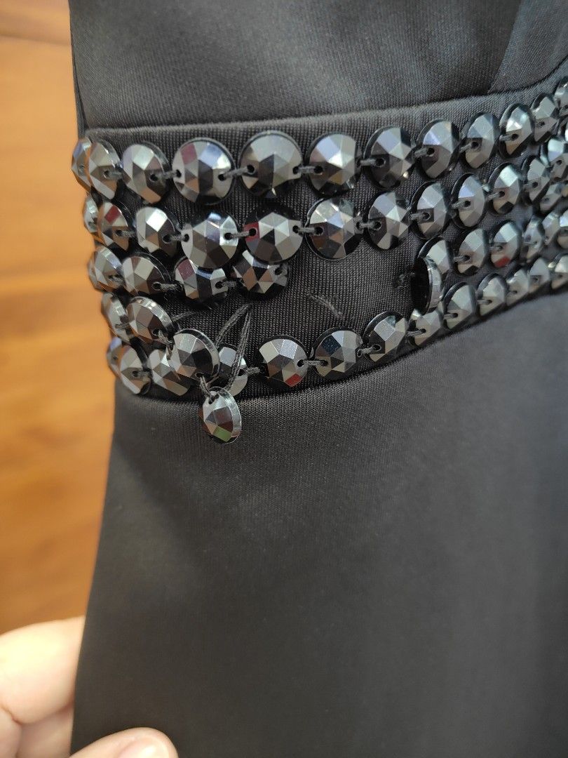 Black Embellished Halter Dress (Category: Dresses) located in Caloocan City. Submitted by cssasot (Listing ID 1401702496, Image 3). Description: Elegant black dress with embellished details. Features a halter neckline and a knee-length cut. The dress has a zipper closure at the back. Embellishments are present around the neckline and waist area. There is a small slit on the side. slight damage sa design pero pwedeng bilan ng buttons pantapal Can 