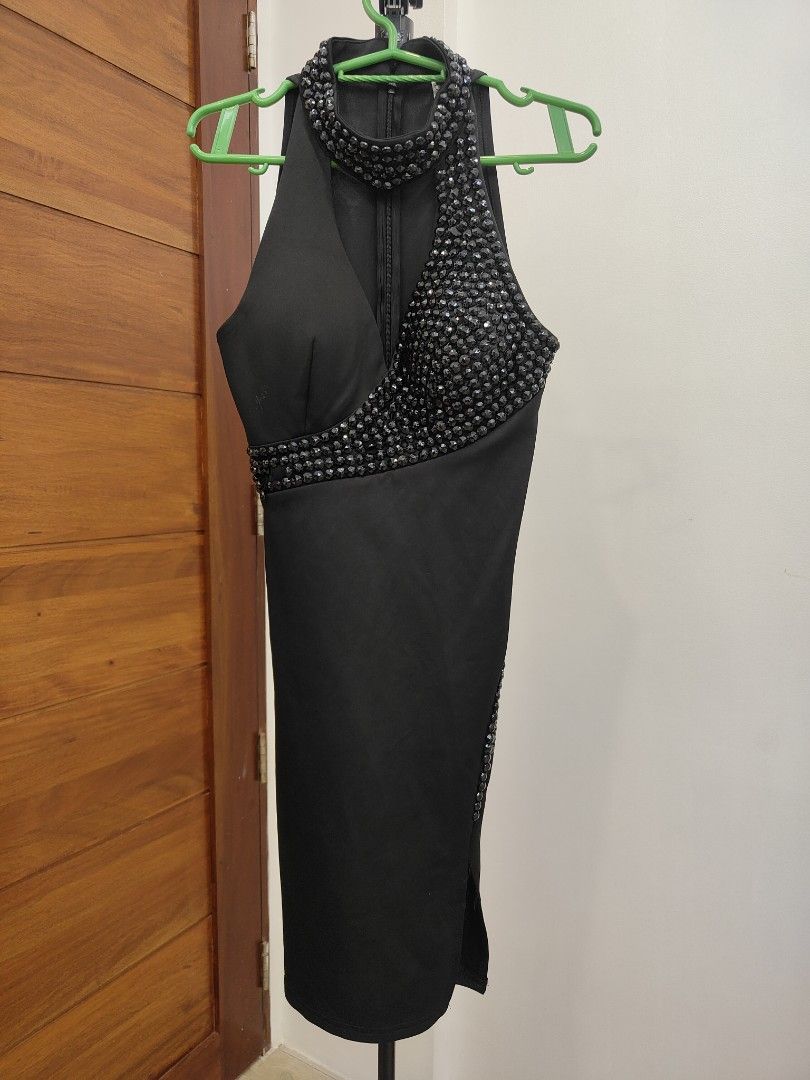 Black Embellished Halter Dress (Category: Dresses) located in Caloocan City. Submitted by cssasot (Listing ID 1401702496, Image 1). Description: Elegant black dress with embellished details. Features a halter neckline and a knee-length cut. The dress has a zipper closure at the back. Embellishments are present around the neckline and waist area. There is a small slit on the side. slight damage sa design pero pwedeng bilan ng buttons pantapal Can 
