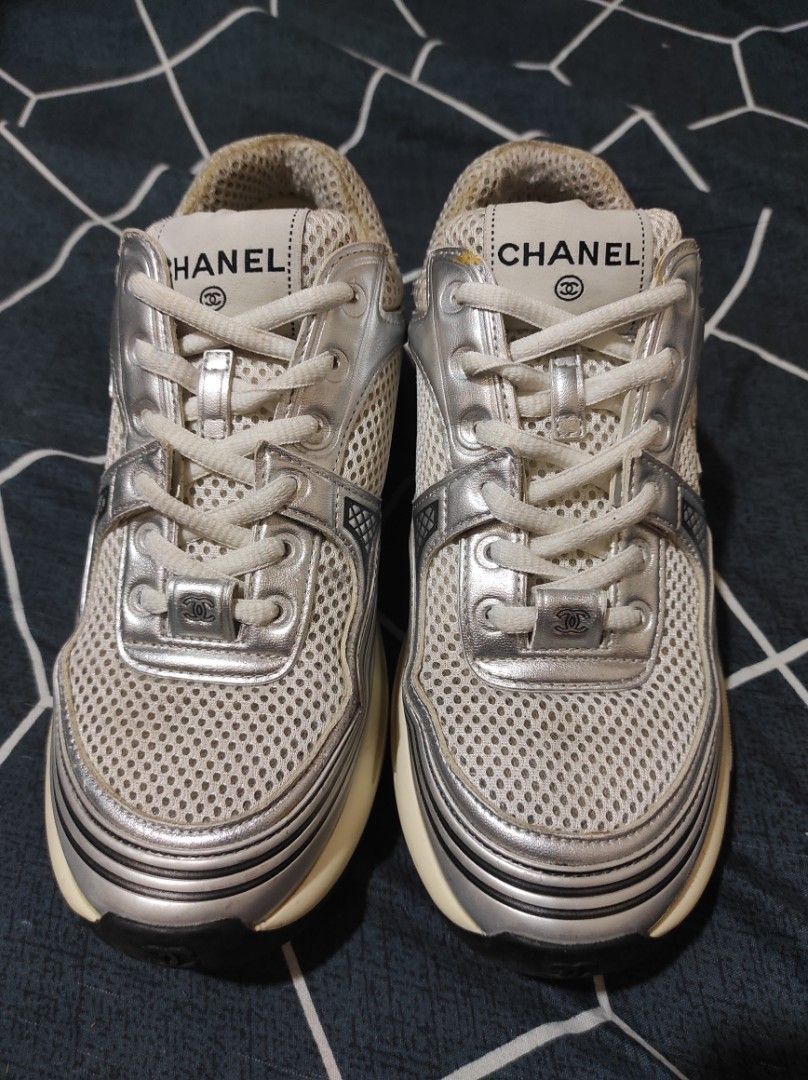 Chanel metallic trainers (Category: Sneakers & Footwear) located in Manila. Submitted by luxxxxxxxx.x (Listing ID 1401647136, Image 2). Description: Chanel sneakers. Features a mesh upper with silver accents and the iconic Chanel logo. The sneakers are size 36 and made in Italy. The soles show some wear. The shoes have white laces and a cushioned sole for comfort. The Chanel logo is visible on the tongue and the sole..
