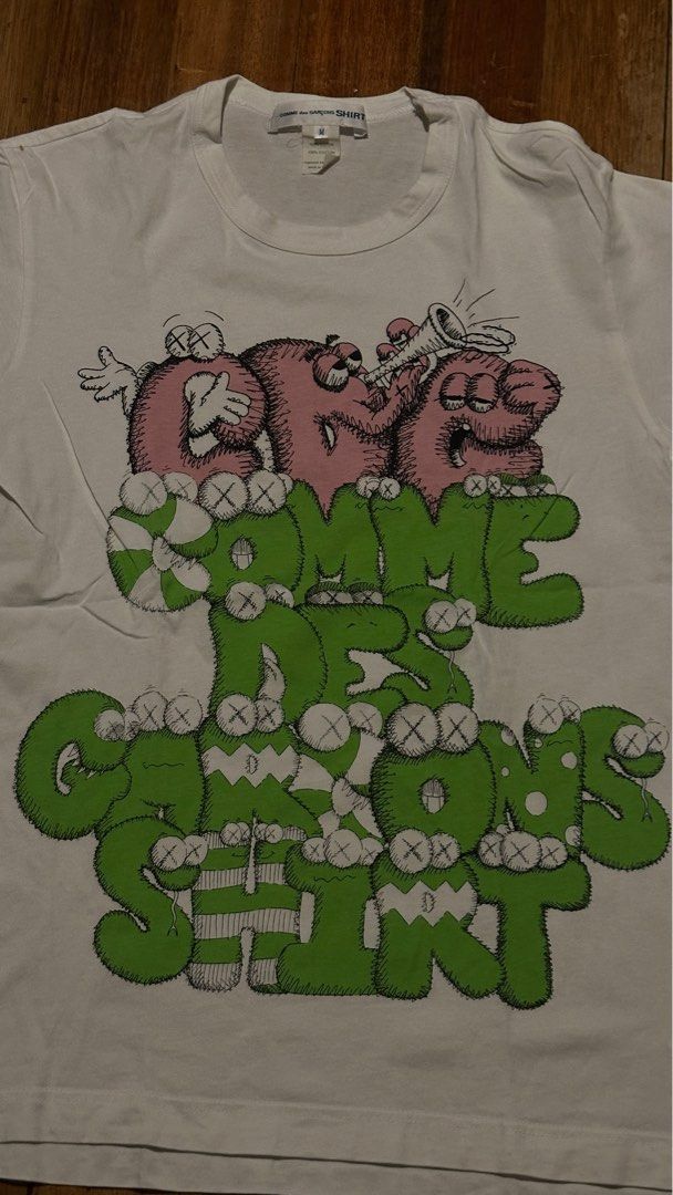 Comme des Garcons Shirt x KAWS Graphic Tee (Category: Luxury Apparel) located in Quezon City. Submitted by area008 (Listing ID 1401655588, Image 2). Description: Kaws x Comme des Garçons white graphic shirt AUTHENTIC CONDITION 9.5/10 May stain sa left top shoulder pero not permanent damage.